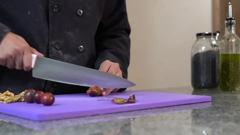 Unrecognizable hands of a female chef chopping cherry tomatoes on a purple .. Stock Footage 282310693