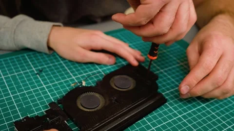 Unrecognizable hands securing laptop cooling system, tightening screws with Stock Footage 303281285