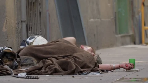 Unrecognizable Heroin Junkie sleeping in the street with his dog. During day Stock Footage