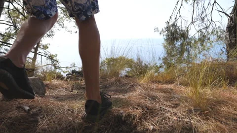 Unrecognizable hiker with backpack reaching up top of mountain with ocean at Видео 331395332