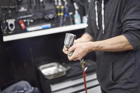 Unrecognizable hispanic worker preparing a spray paint gun in his bike worksh Stock Photos