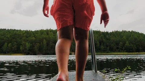 Unrecognizable kid diving into lake on a cloudy evening Stockbeeldmateriaal 93997674