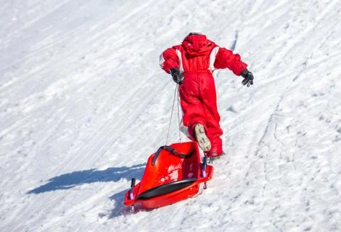 Unrecognizable kid pulling sled on slope Stock Photos