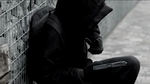 Unrecognizable killer, bandit, or man in a hood and mask leaning against a wall Stock Footage 320604590