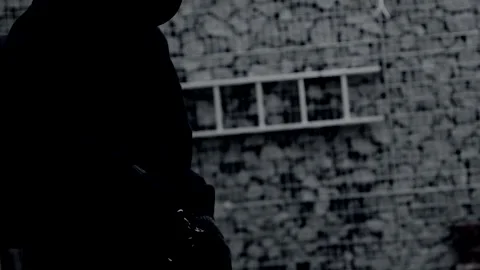 Unrecognizable killer, bandit, or man in a hood and mask leaning against a wall Stock Footage 324471036