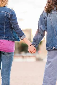 Unrecognizable lesbian couple holding hands. Young dating together in a female Stock Photos
