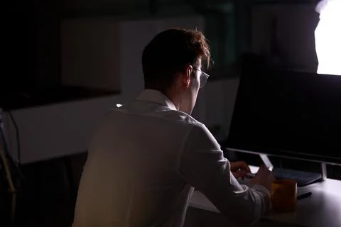 Unrecognizable Male Programmer Writing Code on Computer at Night Sitting At Stock Photos