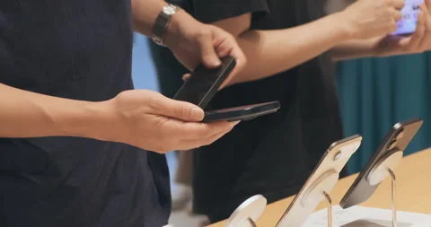 Unrecognizable man approaches stand with iPhone17 smartphones. Shoppers try iPho Stock Footage 322082716
