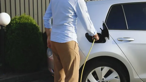 Unrecognizable man attaching power cable to electric car. Electric vehicle Stock Footage 200845247