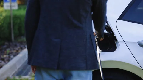 Unrecognizable man attaching power cable to electric car. Electric vehicle Stock Footage 249172869