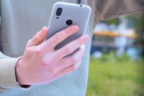 Unrecognizable man browsing the internet using mobile device outdoors. Stock Photos