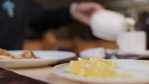 Unrecognizable man in cafe pouring tea into cup, having breakfast Video stock 73610159
