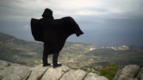 Unrecognizable man with cape swinging by the wind on top of mountain. Mysteri Video stock 153145219