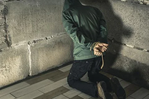 An unrecognizable man is captured in the basement bound by a rope hand Stock Photos