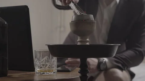 Unrecognizable man changing coal in hookah and typing on laptop. Caucasian Stock Footage 131079064