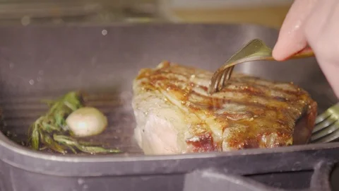Unrecognizable man chef's hands using two forks are rotaring a juicy beef steak Stock Footage 104455416