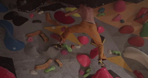Unrecognizable man climbing wall in dark gym Stock Footage 259982765