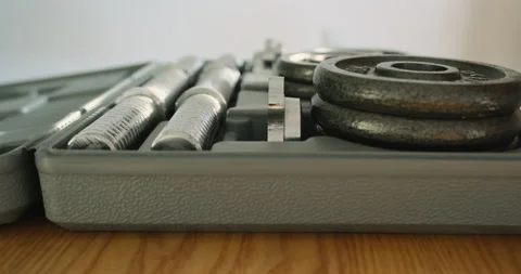 Unrecognizable man close plastic case with a set of dumbbells. Takes out the Video stock 220370419