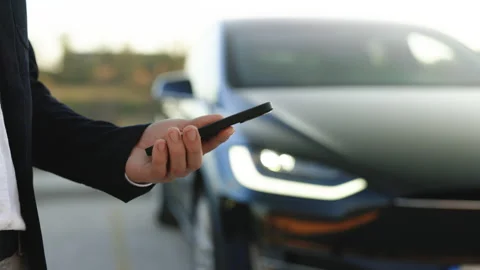 Unrecognizable man controls a self-driving electric car using mobile application Stock Footage 220201951