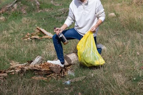 Unrecognizable man crouching down picking up bottle of alcohol after a music  写真素材