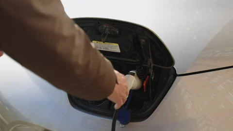 Unrecognizable man disconnects charging cable to electric vehicle. Male hand Stock Footage 196001783