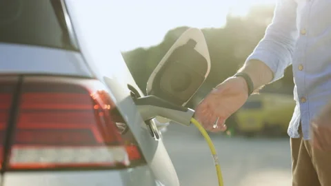 Unrecognizable man disconnects charging cable to to electric vehicle using Video stock 200972435