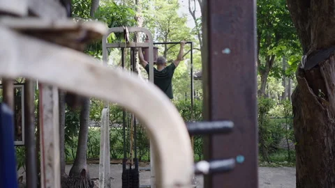 Unrecognizable man doing pullups in a park in the background Stock Footage 265581277