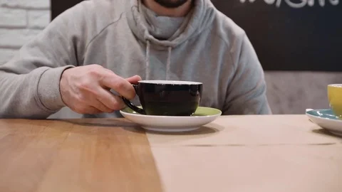 An unrecognizable man drinking tea from a black cup in a restaurant. Close-up Video stock 82446015