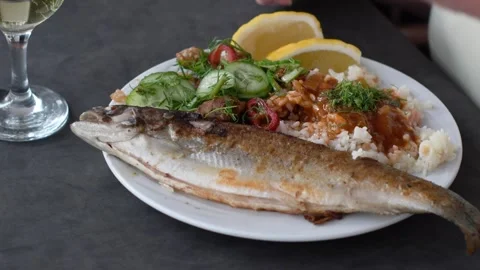 Unrecognizable man eating fried sea bass with cutlery served with rice, fresh Vidéo 285187986