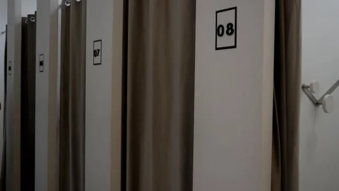 An unrecognizable man emerges from a fitting room, choosing clothes Stock-Footage 311571699