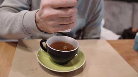 An unrecognizable man with excess weight puts a sweetener in tea, the Video stock 82445708