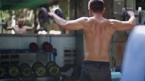 An unrecognizable man exercises his shoulders with weights Video stock 265569382