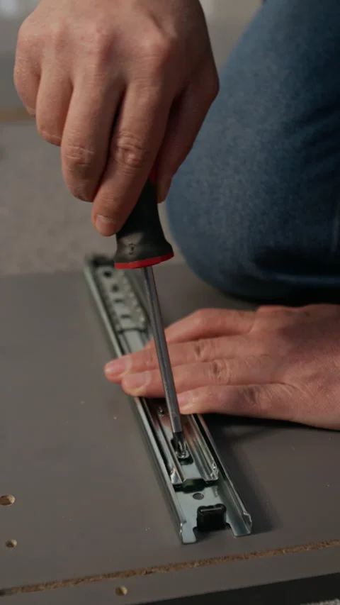 Unrecognizable Man Fixing Runner to Flatpack Cabinet Panel with Screwdriver Stock Footage 330510096
