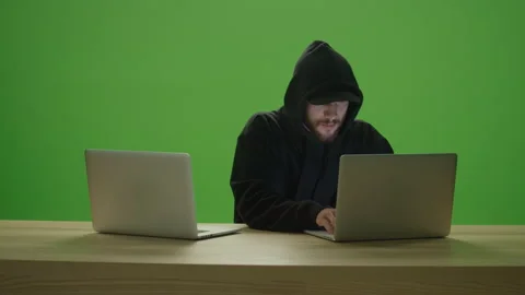 Unrecognizable Man Hacker Wearing Sweatshirt, Hood and Cap Typing on 2 Laptops Video stock 220464175