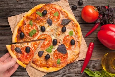 Unrecognizable man hand taking sliced piece of italian pizza margherita with  Stock Photos