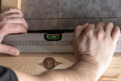 Unrecognizable man hands using waterpass level for building wooden plank fr.. Foto stock