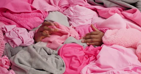 Unrecognizable man has dark skin covered with stack of laundry touches softness Stock Footage 156967784