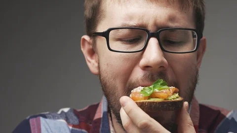 Unrecognizable man is having breakfast. Pours milk foam in coffee, two avocado Stock Footage 104845484