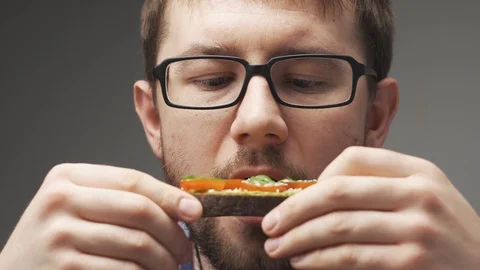 Unrecognizable man is having breakfast. Pours milk foam in coffee, two avocado Stock Footage 104845598