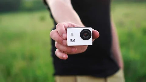 Unrecognizable man holding or showing small white action camera Stock Footage 132933834