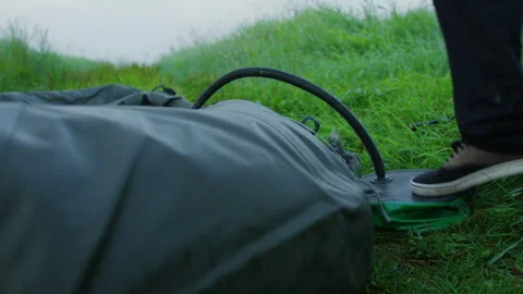An unrecognizable man inflates a boat with a pump in the morning by the lake Stock Footage 248442313