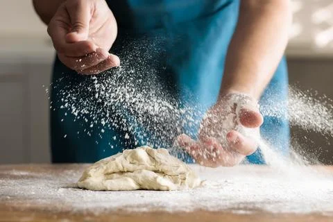 Unrecognizable man kneading by hand in kitchen, on table. Spreading flour Stock Photos