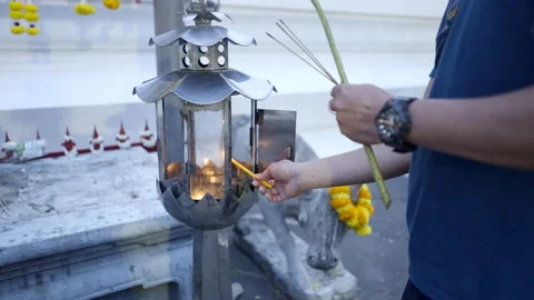 Unrecognizable man lighting a candle at Buddhist temple in Thailand. Religious Vidéo 210853860