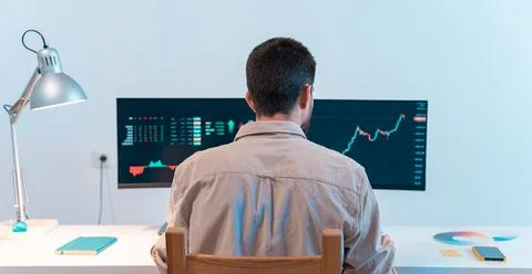 Unrecognizable man looking at computer checking stock exchange market trader Stock Photos