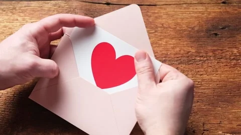 An unrecognizable man opens an envelope with a red heart. Love letter, valent Stock Footage 169100302
