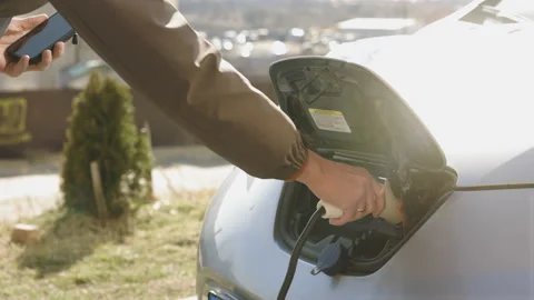Unrecognizable man plugging electric car from charging station. Senior is Video stock 196001828