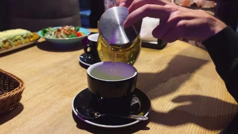 Unrecognizable man pours tea from a teapot in a restaurant or cafe. Stock Footage 255045618
