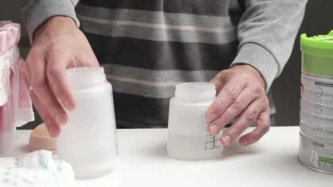 Unrecognizable man preparing baby bottle of powdered milk Stock Footage 219735162