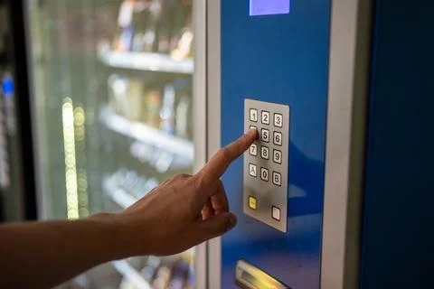 Unrecognizable man presses vending machine buttons for snacks with water. F.. Stock Photos