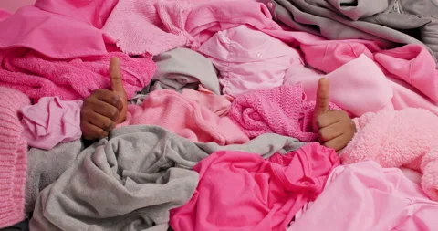 Unrecognizable man raises hands up through pile of laundry makes like gesture Stock Footage 156633841